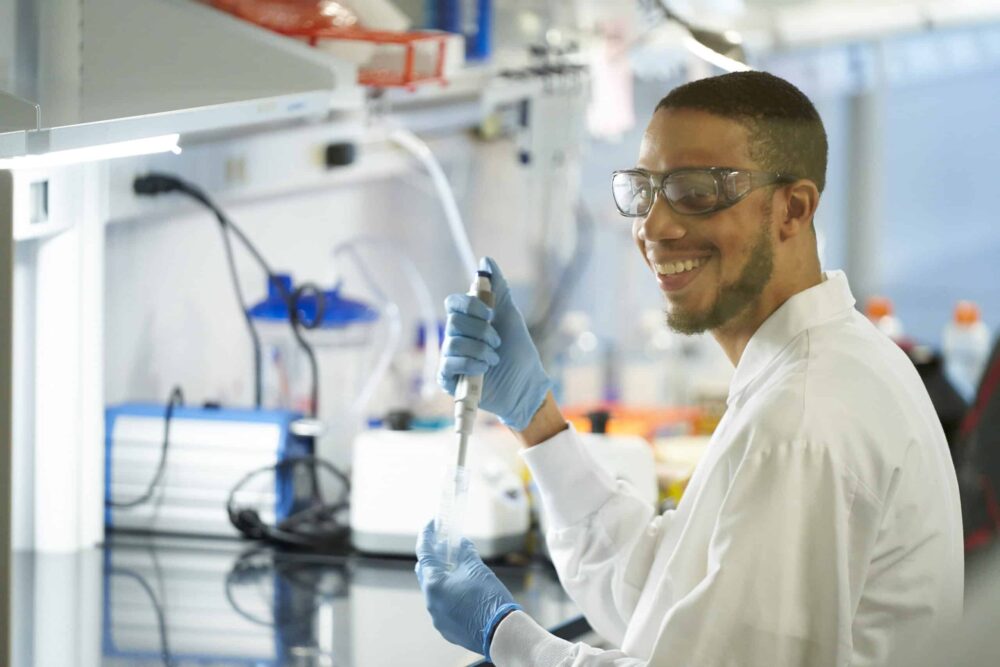 Man in a lab coat smiling while working in a CIC shared lab space