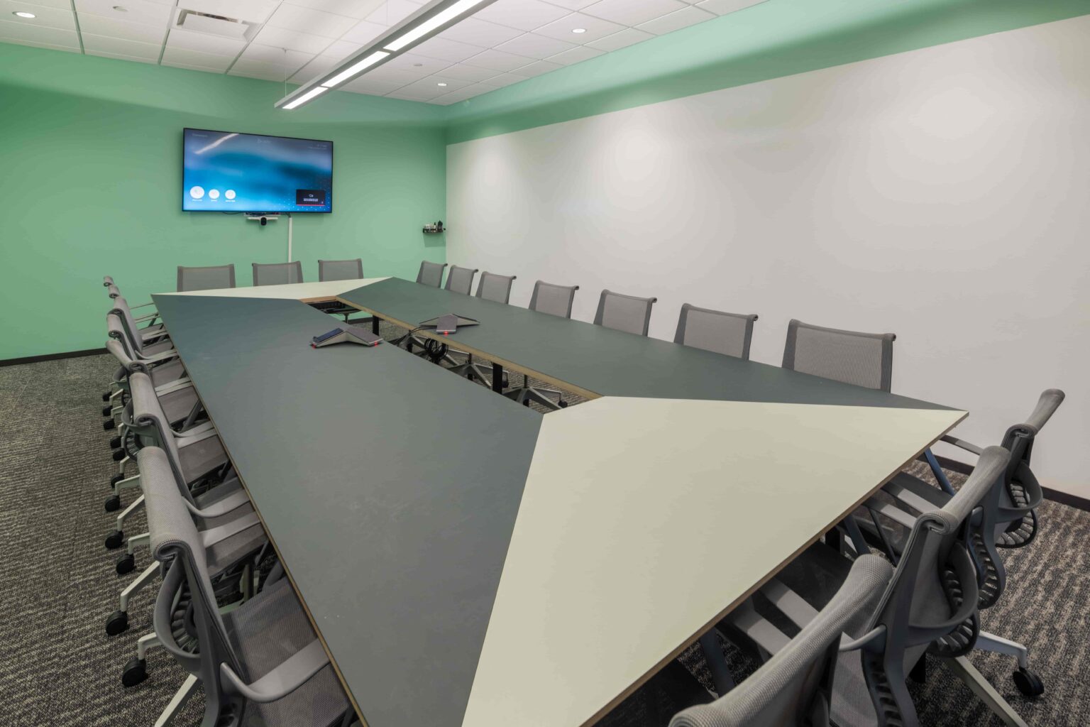 A spacious CIC conference room with table, chairs, TV monitor, video conferencing, and whiteboard