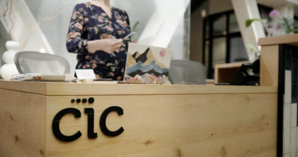 CIC wooden front desk with black CIC logo and a person standing behind the desk.