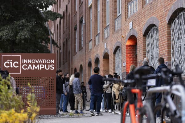Pictured is the outside of the CIC Berlin building with the campus sign and people waiting outside to go in for an event.
